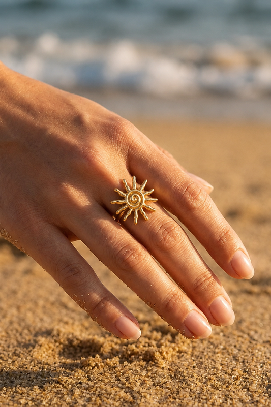 Bague soleil spirale portée en bord de mer – grande bague dorée sculptée rayons organiques, look statement estival éditorial – Bijoux Incandescence
