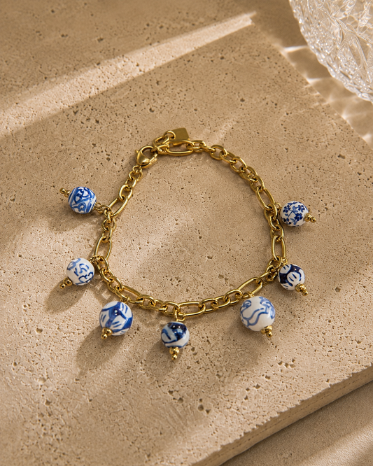 Bracelet charms perles bleues et blanches en céramique motifs porcelaine – chaîne dorée en acier inoxydable avec charm feuille, style artisanal chic – Bijoux Incandescence