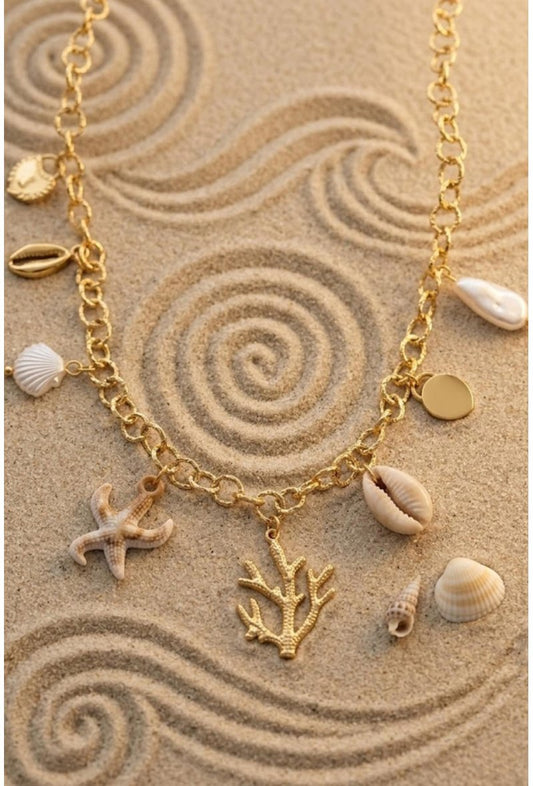 Collier charms corail posé sur sable – chaîne dorée grosse maille avec corail sculpté, cauris, coquillages naturels et étoile de mer, ambiance bord de mer – Bijoux Incandescence