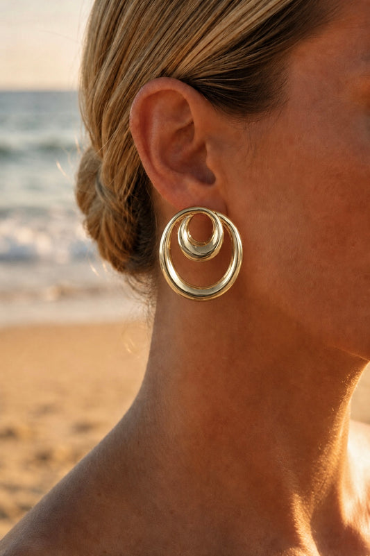 Boucles d'oreilles cercles entrelacés portées – grandes puces dorées architecturales double cercle, look statement luxe – Bijoux Incandescence