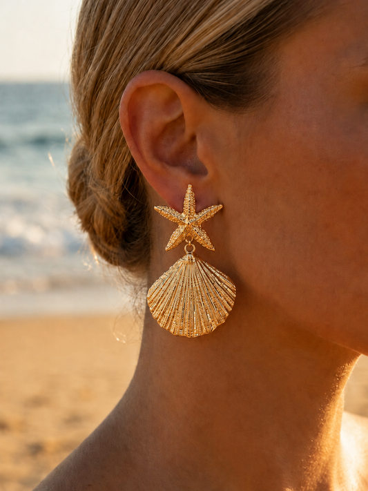 Boucles d'oreilles coquillage dorées portées en bord de mer – grandes boucles statement étoile de mer et coquille Saint-Jacques – Bijoux Incandescence