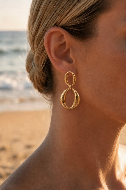 Boucles d'oreilles double anneaux dorées portées en bord de mer – pendantes ovales sculpturales en acier inoxydable, style statement – Bijoux Incandescence