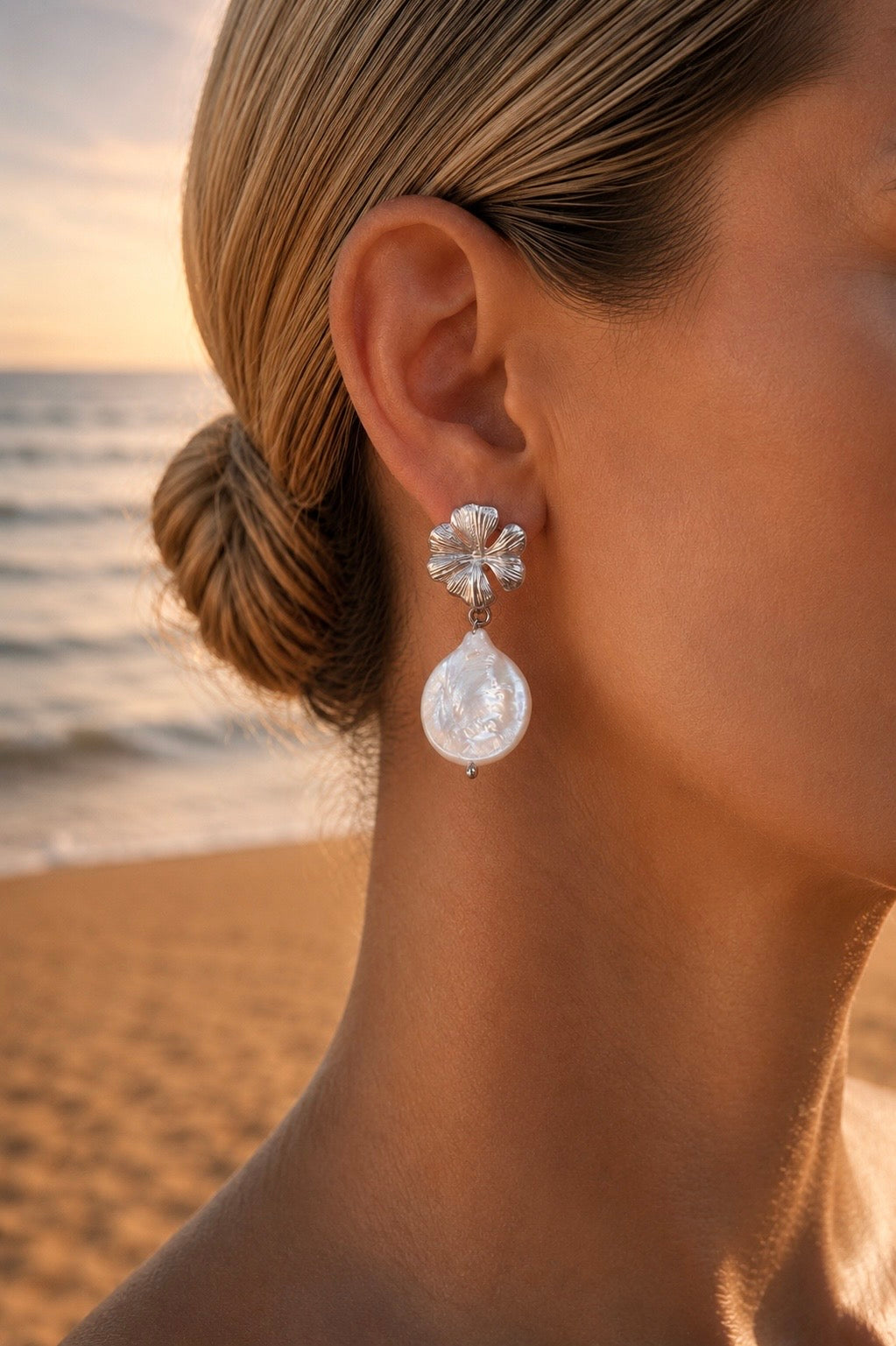 Boucles d'oreilles fleur et perle goutte nacrée argentées portées – puce hibiscus finement striée en relief et grande perle baroque irisée, ambiance bord de mer – Bijoux Incandescence