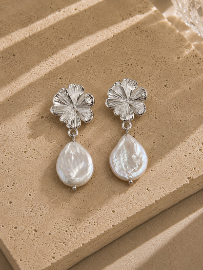 Boucles d'oreilles fleur et perle goutte nacrée argentées – puce hibiscus finement striée en relief et grande perle baroque nacrée irisée, style élégant naturel – Bijoux Incandescence