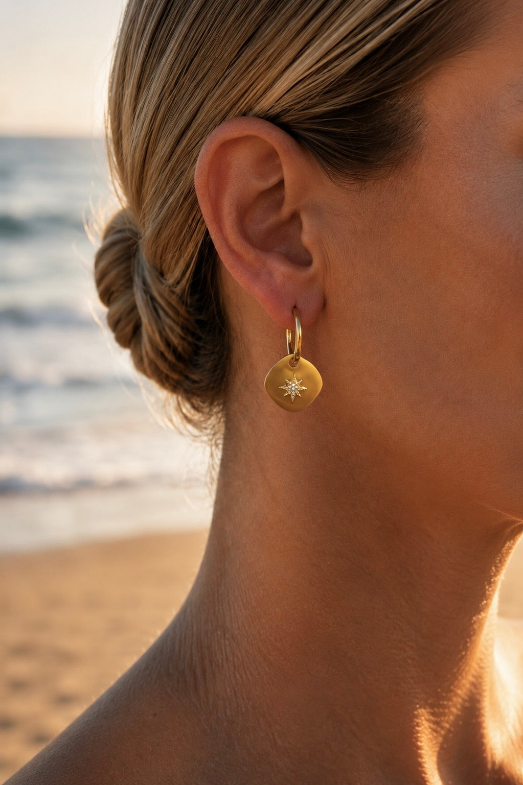 Boucles d'oreilles médaillon étoile portées – créoles dorées avec pendentif étoile polaire scintillante – Bijoux Incandescence