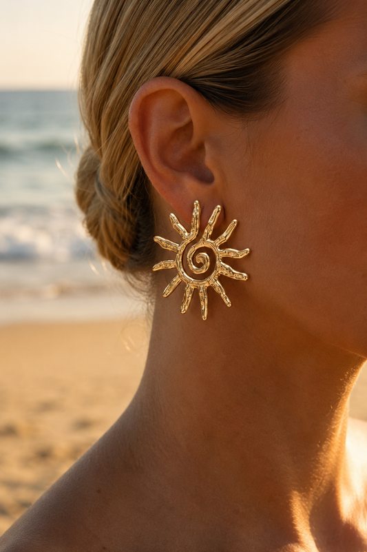 Boucles d'oreilles soleil spirale dorées portées en bord de mer – grandes puces soleil martelées rayons texturés, look statement estival – Bijoux Incandescence