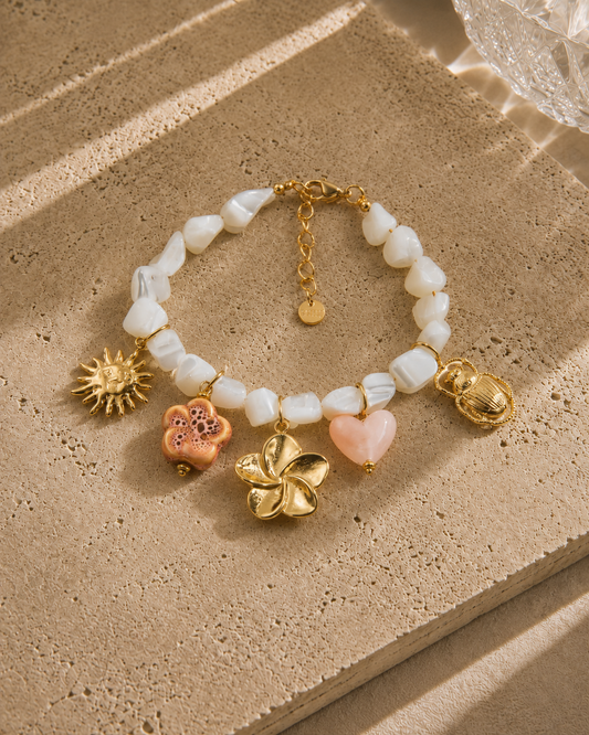 Bracelet charms boheme – perles nacre blanche avec charms soleil doré, fleur corail, grande fleur dorée, cœur rose et scarabée doré, style estival romantique – Bijoux Incandescence
