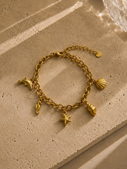 Bracelet charms dauphin doré – chaîne épaisse avec 5 charms marins : coquille, escargot, étoile de mer, hippocampe et dauphin – Bijoux Incandescence