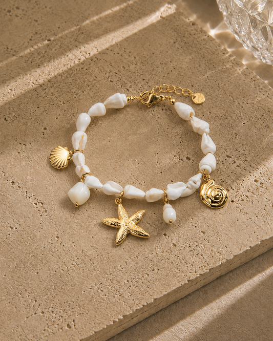 Bracelet charms étoile marin – perles nacre blanche baroques avec charms étoile de mer dorée, coquille Saint-Jacques et escargot de mer dorés – Bijoux Incandescence