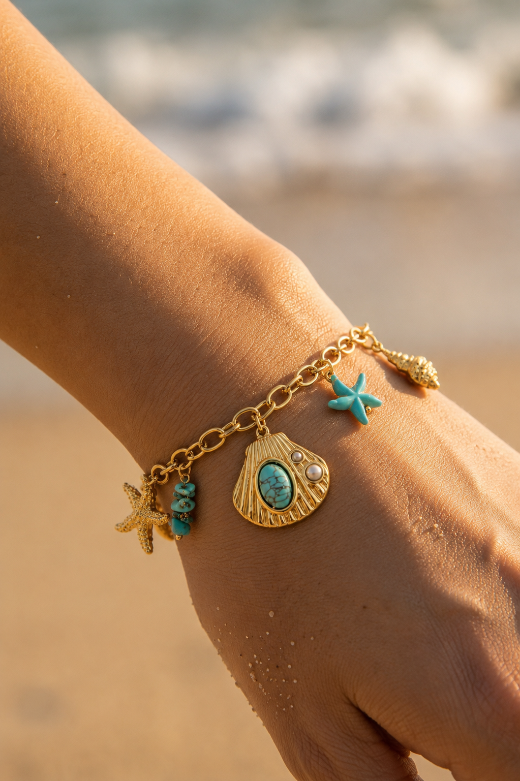 Bracelet charms mer turquoise doré porté au poignet – coquille dorée, pierre turquoise, étoile de mer et perles – Bijoux Incandescence