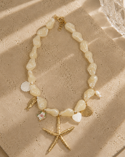 Collier charms bord de plage – perles baroques nacre blanche, grande étoile de mer dorée, coquillages, poisson doré et cœur nacre – Bijoux Incandescence